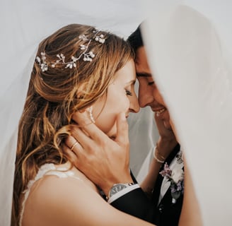 sposo e sposa abbracciati sotto al velo