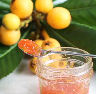Loquat jam in a spoon with fresh loquats behind. Photo from the recipe page at the link below.