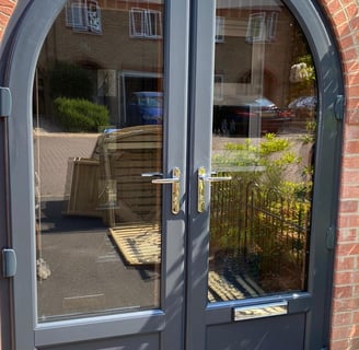 anthracite grey front door with unusual arched shape and reflective glass