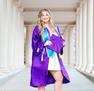 A woman in a purple graduation gown holding a purple graduation cap