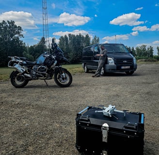Dronekoffer, motorfiets en bestelwagen staan klaar voor drone-inspectie op locatie met lichtmast op de achtergrond