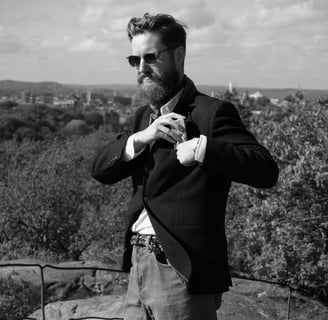 a man in a suit and sunglasses standing on a hilll