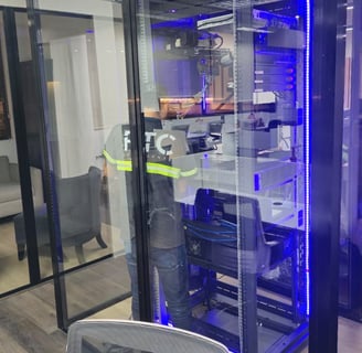 Técnico trabajando dentro de cuarto de servidores con gabinete iluminado.
