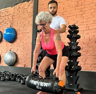 mulher mais velha treinando com auxilio de instrutor de funcional