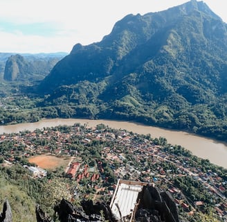 a mountain view of a town with a river and mountains in the background