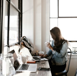 a woman sitting at a desk with a laptop and a cup of coffee