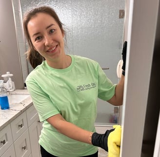 a woman in a green shirt is cleaning a bathroom