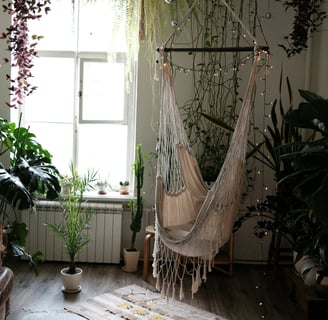 Fauteuil suspendu style bohème devant une fenêtre, nombreuses plantes