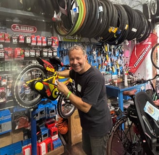 Federico, il proprietario di abicicomeprima, sorride intento ad aggiustare una bici da bambino