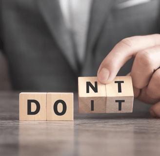 a person holding a wooden block with the words don't do it
