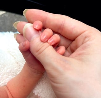 Newborn baby holding mothers thumb for the first time, symbolizing early motherhood bond and emotional connection