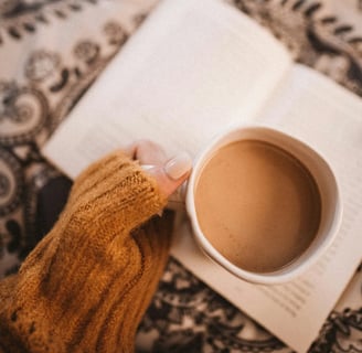 Main de femme tenant une tasse de café sur un livre, symbole d’ancrage doux et d’exploration intérie