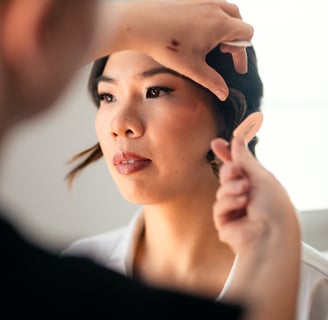 Makeup artist adjusting the bride's hair after makeup application.