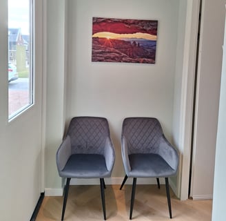 2 stoelen in een kamer met een schilderij aan de muur
