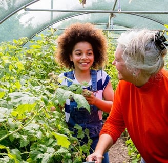 An elderly woman with a preteen girl in the greenhouse