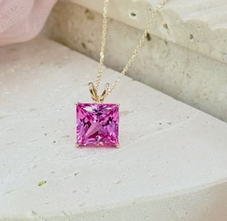 The image showcases a stunning princess-cut pink sapphire pendant necklace, elegantly set in a yello