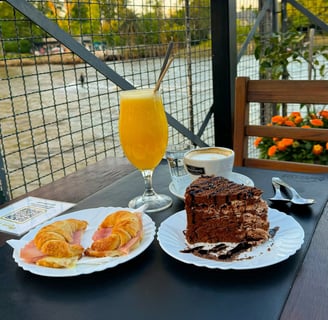Bolo de chocolate, Medialunas recheadas com presunto e queijo, café e suco de laranja sobre uma mesa