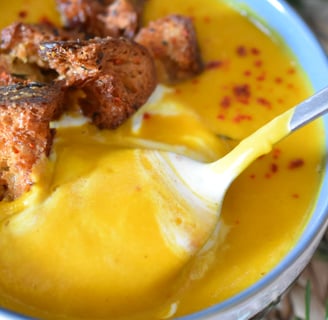 Une cuillère dans un bol de soupe avec des croûtons