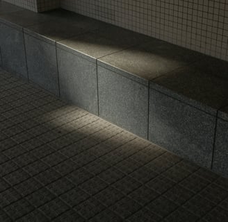 Sunlight casting shadows on a concrete tiled seating area and wall.