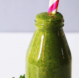 a bottle of green smoothie with a strawberries and a strawberries