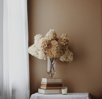 Vase de fleurs séchées sur des livres, symbole d’un espace calme, doux et conscient de ressourcement