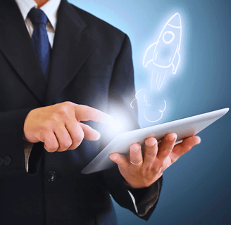 A man in a black suit and tie holds a tablet, touching the screen with his index finger as a holographic rocket ship emerges.