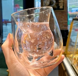 a person holding a cate shaped double wall glass