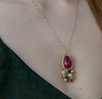 Foto do busto de uma mulher mostrando um colar com pendente de pedra vermelho e uma blusa com decote