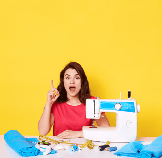 Mujer diseñadora con máquina de coser, telas y herramientas de confección en una mesa.