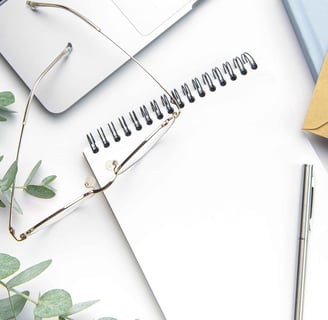 Image of a notebook with a laptop, glasses and eucalyptus leaves