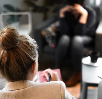 a woman sitting on a couch with a man in a chair