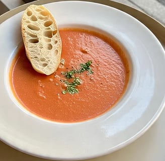 a bowl of soup with breaded bread on a table