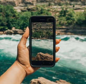 Persona sosteniendo un iPhone Km0 frente a un río, simbolizando la conexión entre tecnología y naturaleza.