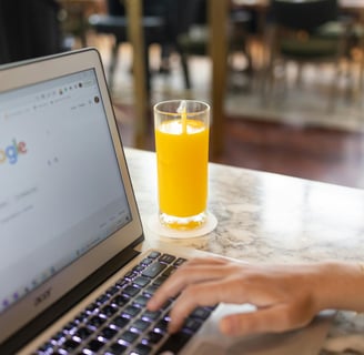 a person using a laptop computer and a glass of orange juice