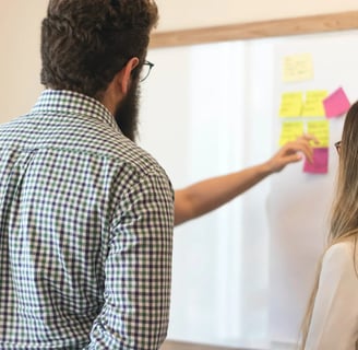 a man and woman standing in front of a white board