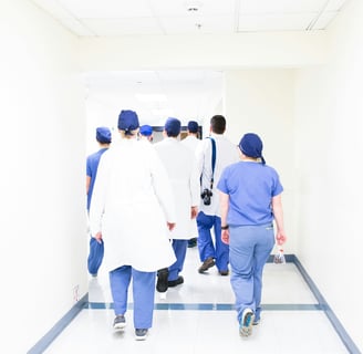 group of doctors and nurses in scrubs walking down a hospital corridor to their OET exam.