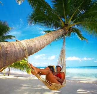 a woman in a bikini top sitting in a hammock reading a book