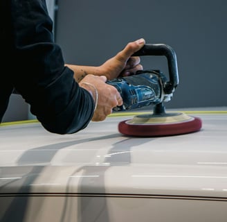 a person using a sander machine to polish a car- buffing a car at fix collision center