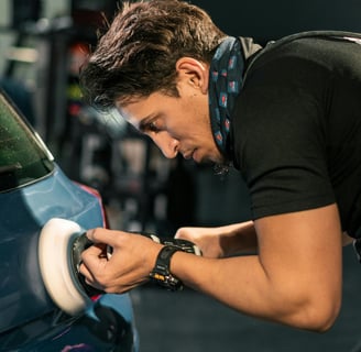 a man in a black shirt is polishing a car