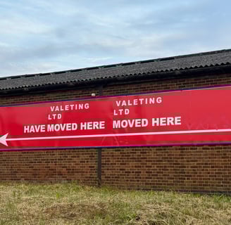 Big red sign on brick wall that reads Valeting Ltd have moved here Valeting Ltd moved here