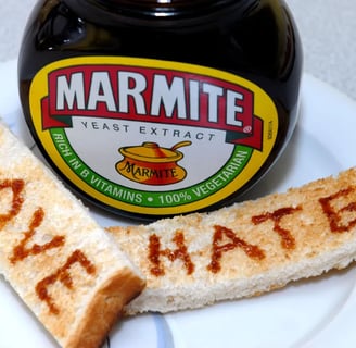 Jar of Marmite on a white plate with two soldiers that read love and hate