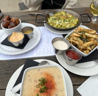 A table with pretzel bites, mac & cheese, french fries, and clam chowder