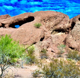 a rock formation in the desert with a blue sky and clouds