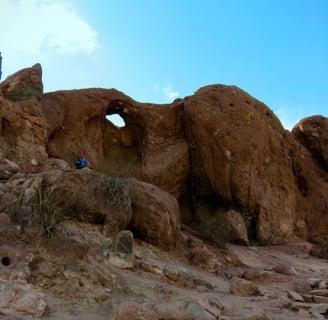 a desert rock formation with a hole showing blue sky behind