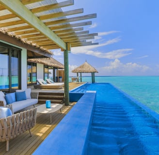 a large pool with a lounge chair and a couch from Velassaru Maldives