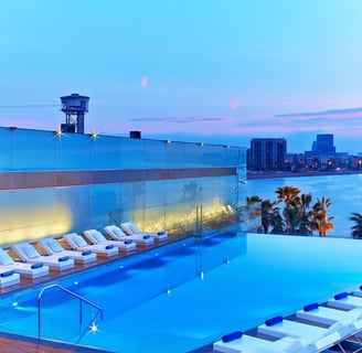 a pool with lounge chairs and a view of the city from W Barcelona hotel