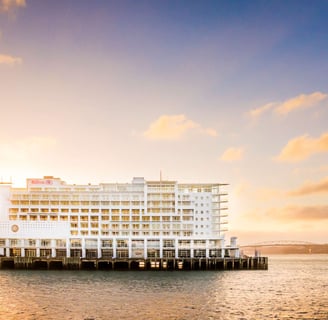 a large white building with a boat in the water from Hilton Auckland hotel