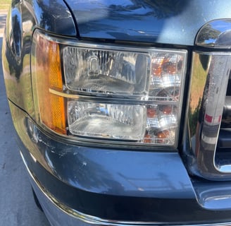 Blue truck seen from the front, with a shiny headlight after restoration, highlighting its new look.