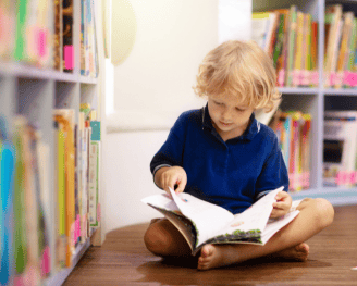 young boy in a library reading a book
