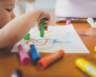 preschooler drawing with markers on paper